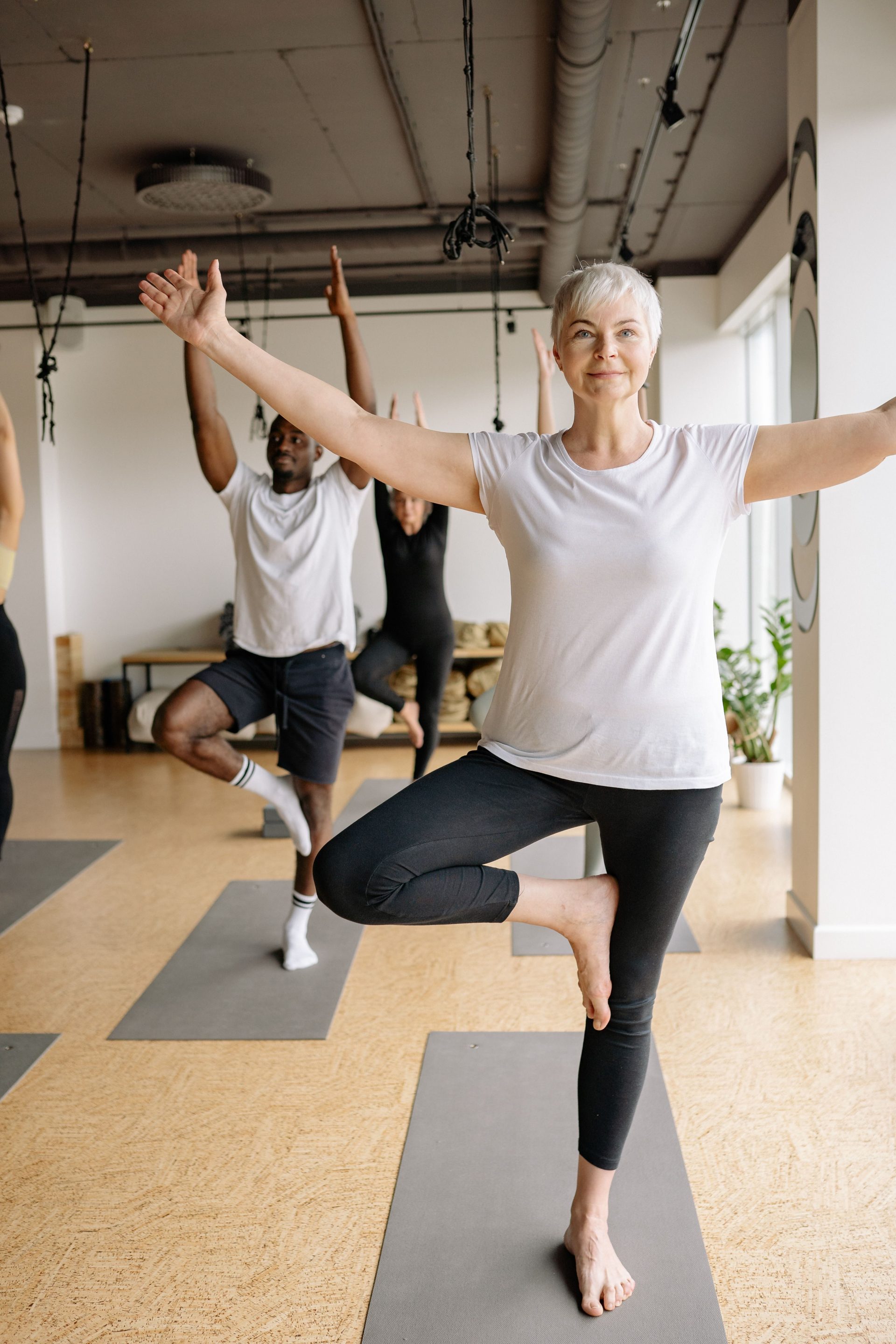 Eine ältere Frau praktiziert Yoga in einer ruhigen Studioatmosphäre und konzentriert sich auf Gleichgewicht und Wohlbefinden.